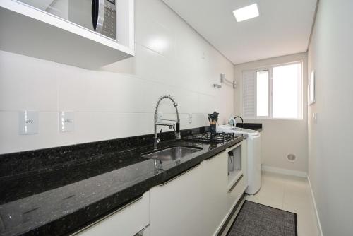 a white kitchen with a sink and a stove at Apartamento Aconchegante em Itajaí - ITJ001 in Itajaí