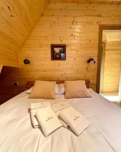 a bed in a wooden cabin with two towels on it at Aurum Cabins in Zlatibor