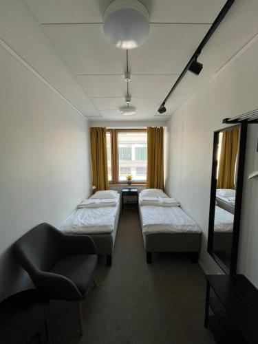 a room with three beds and a chair and a window at Aikatalo Hostel Helsinki in Helsinki