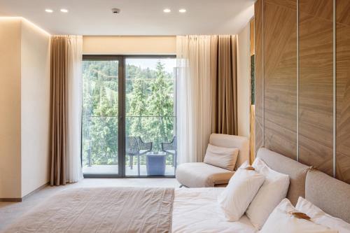 a bedroom with a bed and a chair and a window at Tavel Hotel & SPA in Bukovel