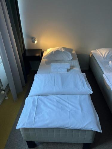 two beds with white sheets and pillows in a room at Aikatalo Hostel Helsinki in Helsinki