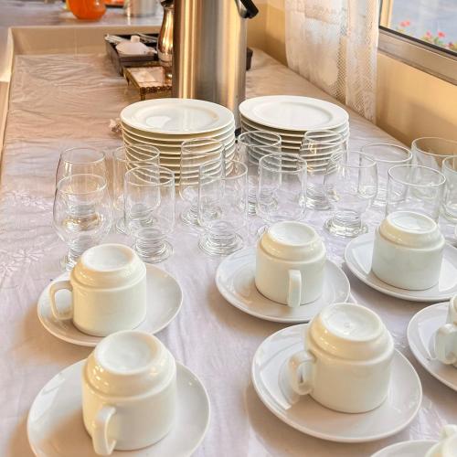a table with white plates and cups and glasses at Hotel Akroama in Corumbaíba