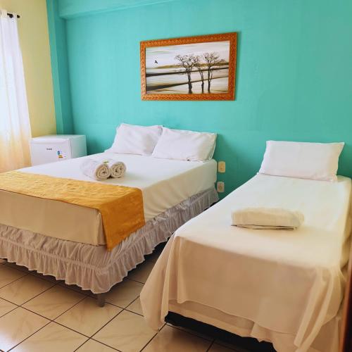 two beds in a room with blue walls at Hotel Akroama in Corumbaíba