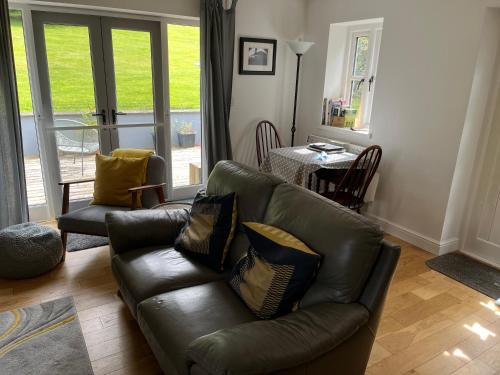 a living room with a leather couch and a table at Maes Y Grove Garden Cottage in Llanddarog