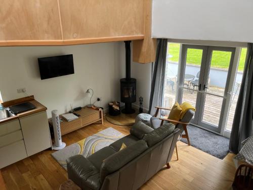 a living room with a couch and a kitchen with a balcony at Maes Y Grove Garden Cottage in Llanddarog