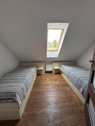 two beds in a room with a window at Anielski Domek in Nieledwia