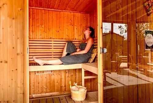 a woman sitting on a bench in a sauna at Mobil-home domaine la yole 5 étoiles in Vendres
