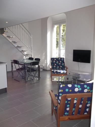 un salon avec une télévision, une table et des chaises dans l'établissement Square Victoria, à Menton