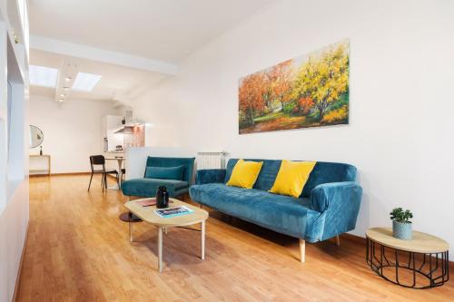 ein Wohnzimmer mit einem blauen Sofa und einem Gemälde an der Wand in der Unterkunft Lungotevere Trastevere Loft in Rom