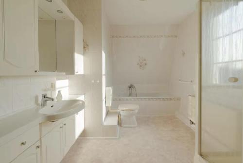 a white bathroom with a sink and a toilet at Entire house with garden - exclusively for your group in Leipzig