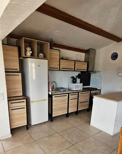 La cuisine est équipée d'un réfrigérateur blanc et d'un four micro-ondes. dans l'établissement Les Roses, à Bézaudun-les-Alpes