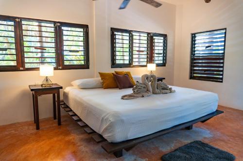 a bedroom with a large white bed with windows at Sol Caribe in Punta Allen