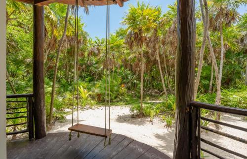 a swing on the porch of a resort with a beach at Sol Caribe in Punta Allen