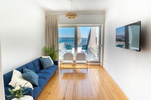 un soggiorno con un divano blu e un balcone di Queen's Ocean Sight - Guest House a Cascais