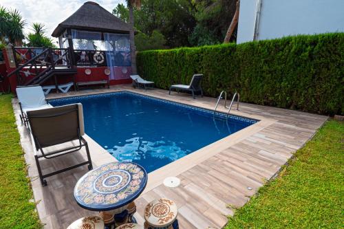 a pool with a table and chairs and a playground at VILLA NABRISA MARBELLA, 5 BEDROOM, PRIVATE POOL, GARDEN, BBQ in Marbella