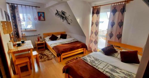 a bedroom with two beds and a table and a desk at Pokoje "U Moniki" in Ząb
