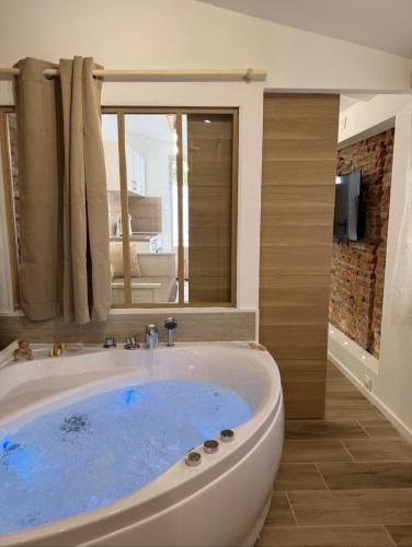 La salle de bains est pourvue d'une grande baignoire et d'une fenêtre. dans l'établissement Escapade Tournefeuille, jacuzzi, balnéo, terrasse, à Tournefeuille