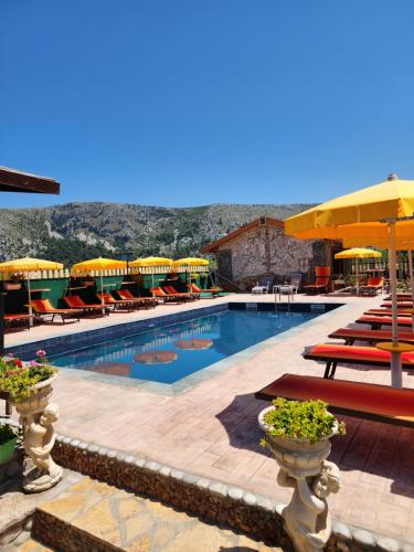 a swimming pool with chairs and umbrellas at Bujtina Syni Zi "Keshtjella" - Shengjin in Shëngjin