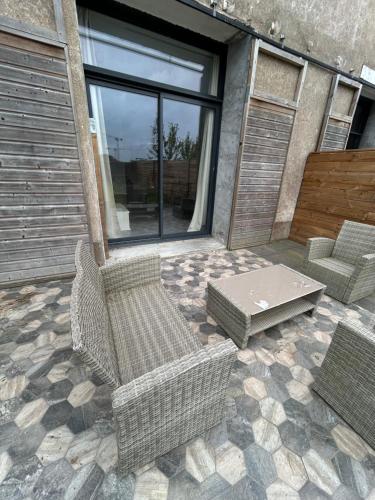 d'une terrasse avec 2 chaises en osier et une table. dans l'établissement chambre meublée Nantaise dans un T3 commun avec terrasse, à Nantes