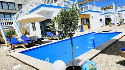a blue swimming pool with blue chairs and an umbrella at Sunshine Bungalow in Schitul