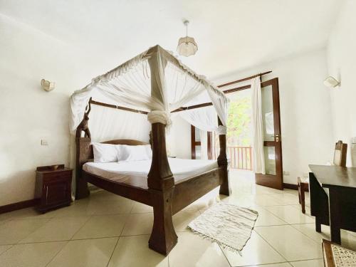 a bedroom with a four poster bed with a canopy at VITA'S BEACH House in Diani Beach