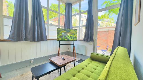 a living room with a green couch and a table at Petit cocon à Douai avec jardin et Netflix in Douai