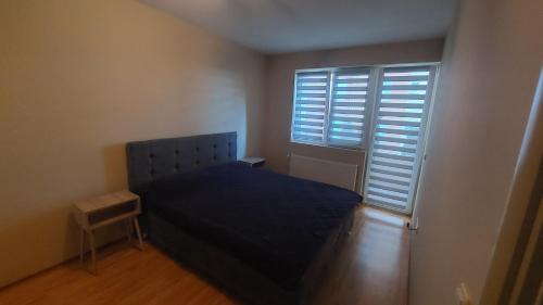 a bedroom with a bed and a window with shutters at Apartman Dona in Jagodina
