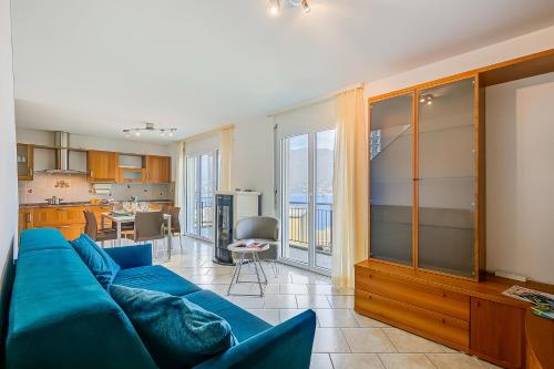 Una sala de estar con un sofá azul y una cocina. en Casa Zaira 1 - Happy Rentals, en Caviano