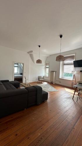 a living room with a black couch and wooden floors at Ostsee FeWo Lübeck in Lübeck