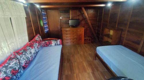 a bedroom with a bed and a dresser and a television at Chalé Aconchego em Atibaia in Atibaia