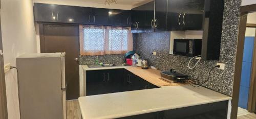 a kitchen with black cabinets and a sink and a refrigerator at Racecourse Apartment in Mba