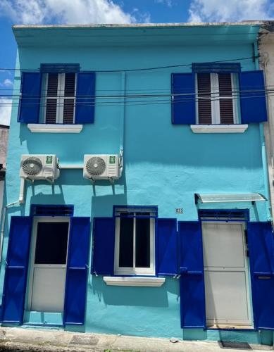 a blue building with two windows and two air conditioners at Appartement l'Amélie in Saint-Pierre