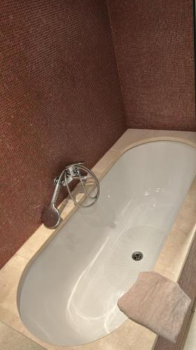 La salle de bains est pourvue d'une baignoire blanche avec un robinet. dans l'établissement Appartement avec balcon dans résidence calme avec gardien -, à Paris