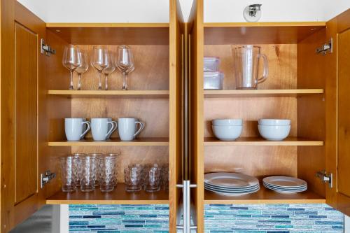 a cupboard with glasses and plates and wine glasses at Marine Surf 18FL Newly Renovated - Free Parking in Honolulu