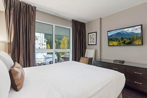 a bedroom with a bed and a desk and a window at Le Chamois by Whistler Premier in Whistler