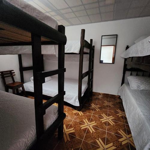 a room with three bunk beds and a tile floor at Hostal Verana in Filandia