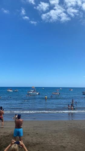 a group of people on the beach with boats in the water at Casa Arena y Mar in Telde