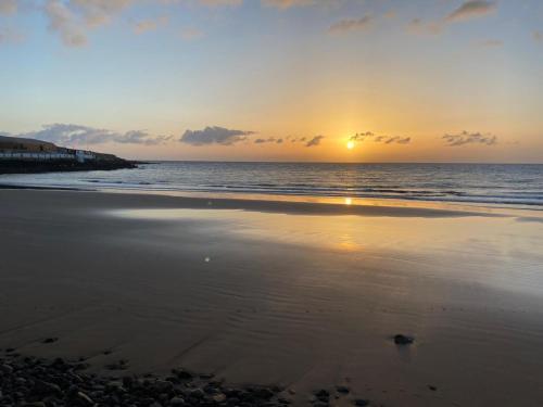 a sunset on a beach with the ocean at Casa Arena y Mar in Telde