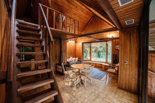 a living room with a table and a spiral staircase at Hotel y Termas Huife in Termas De Huife