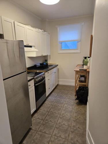 a kitchen with white cabinets and a stainless steel refrigerator at Byward Market Downtown Guesthouse in Ottawa