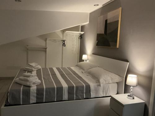 a white bedroom with a bed with a striped blanket at La Casina sul Tetto in Albano Laziale