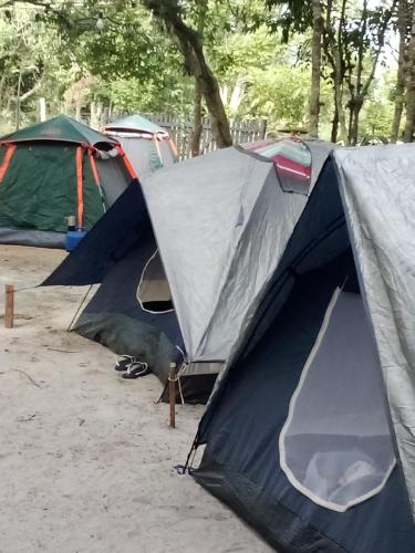 a group of tents sitting in the sand near trees at Excelente Casa na Lagoa Guanandy mais acesso a Lagoa Particular in Itapemirim