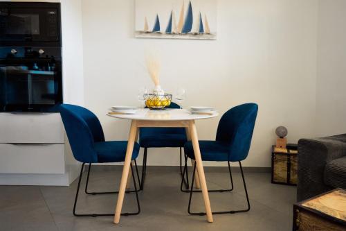 a dining table with blue chairs and a white table at 36 2 l air marin Penthouse Netflix Clim Free park Navette Grands Buffets Accès direct autoroute et plages in Narbonne