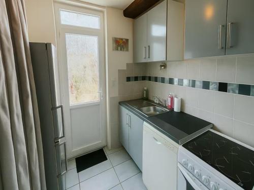 une petite cuisine avec un évier et une fenêtre dans l'établissement Charmante Maison Wifi télé 65 pouces netflix, à Choisy-au-Bac