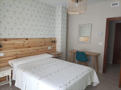 a bedroom with a white bed and a blue chair at Hostal Quiper in Quiroga
