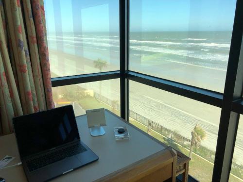 a laptop sitting on a desk in front of a window with a beach at Oceanside Inn Hotel in Daytona Beach Shores