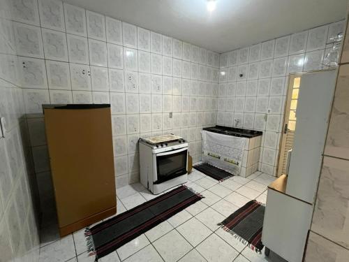 a kitchen with a stove and a tiled wall at Cantinho da val in Aparecida