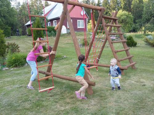 two girls and a boy playing on a wooden swing at Brīvdienu māja Skerškāni in Krāslava