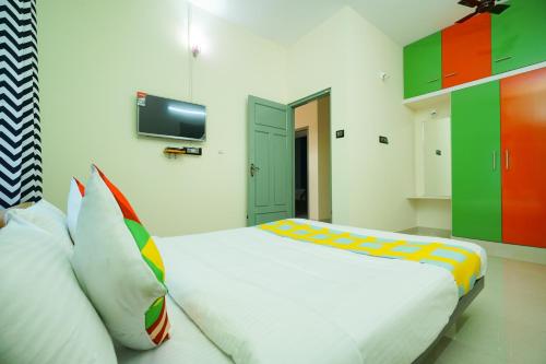 a bedroom with a large white bed with colorful pillows at Hotel O Majestic Stays in Kazhakuttam