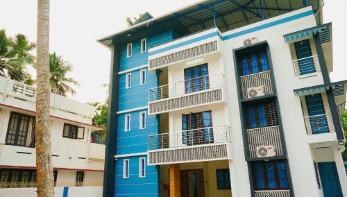 a blue and white building with a palm tree at Hotel O Majestic Stays in Kazhakuttam